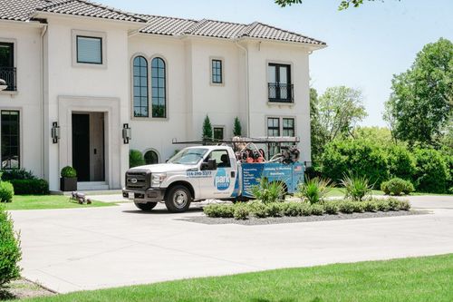 A white truck is parked in front of a large white house.