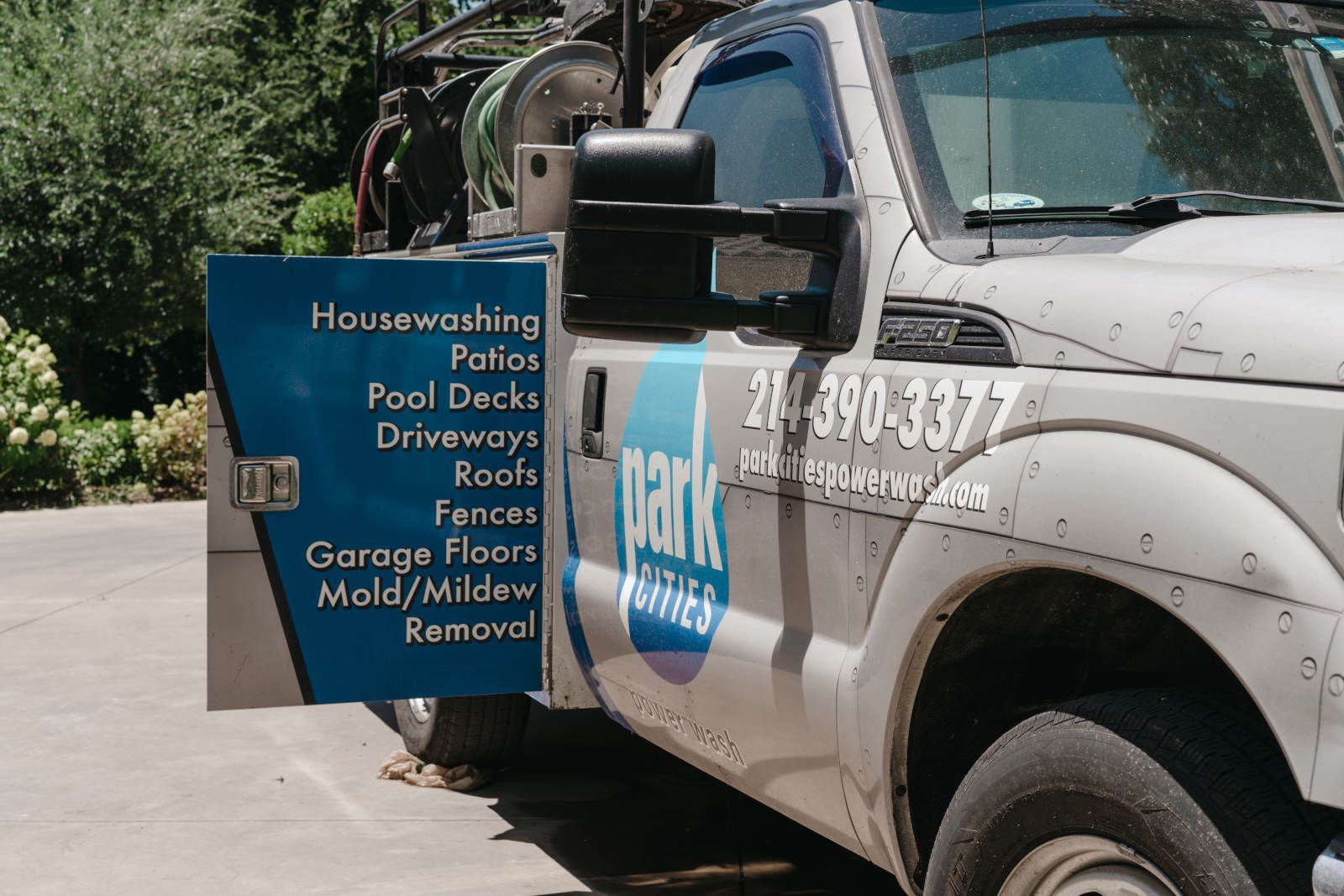 A white truck with a blue sign on the side is parked in a driveway.