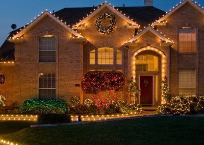 A brick house decorated with christmas lights and a wreath