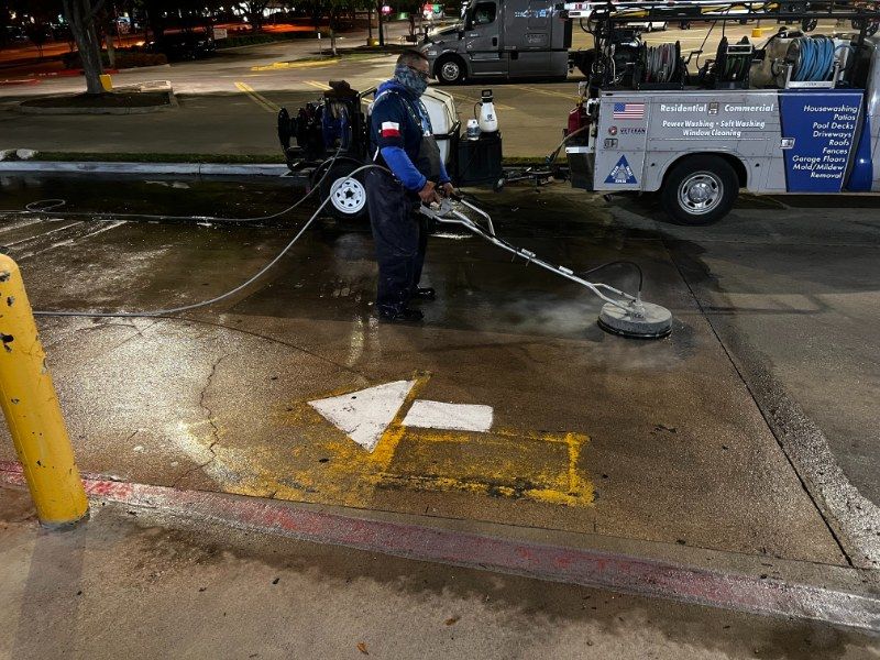 A man is using a machine to clean a parking lot