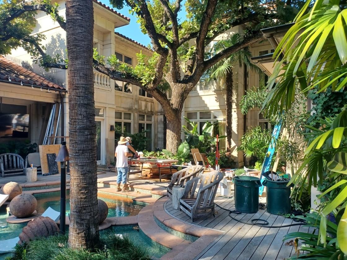 A man is working on a patio in front of a large house.