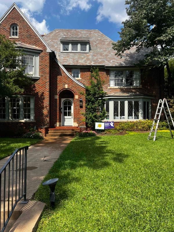 A large brick house with a ladder in front of it.