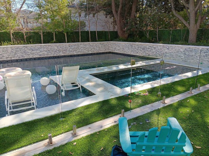 A large swimming pool surrounded by lawn chairs and a blue chair.