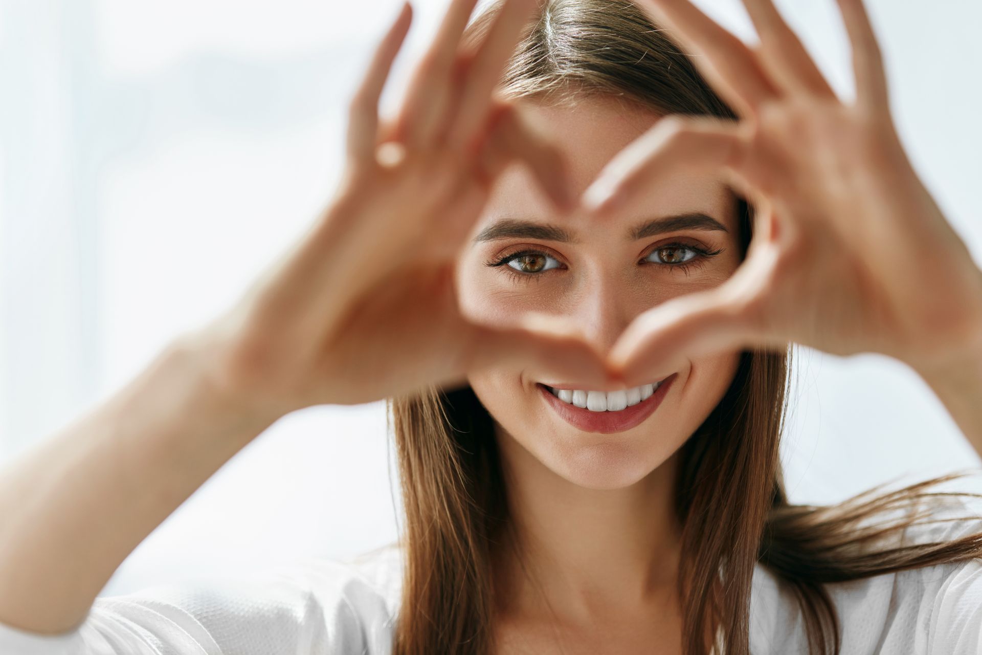 Woman making the sign of a heart in front of her eyebrows