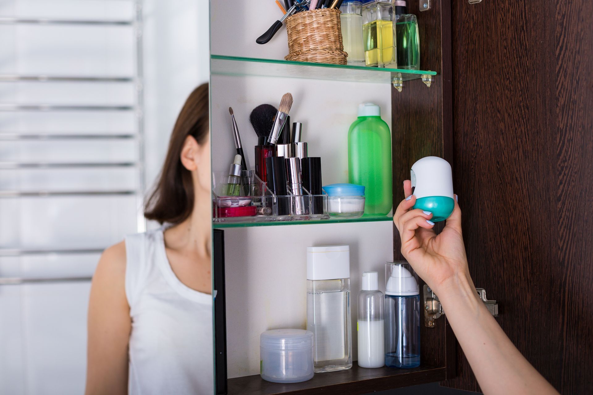 Woman inspecting labels on products in her bathroom cabinet