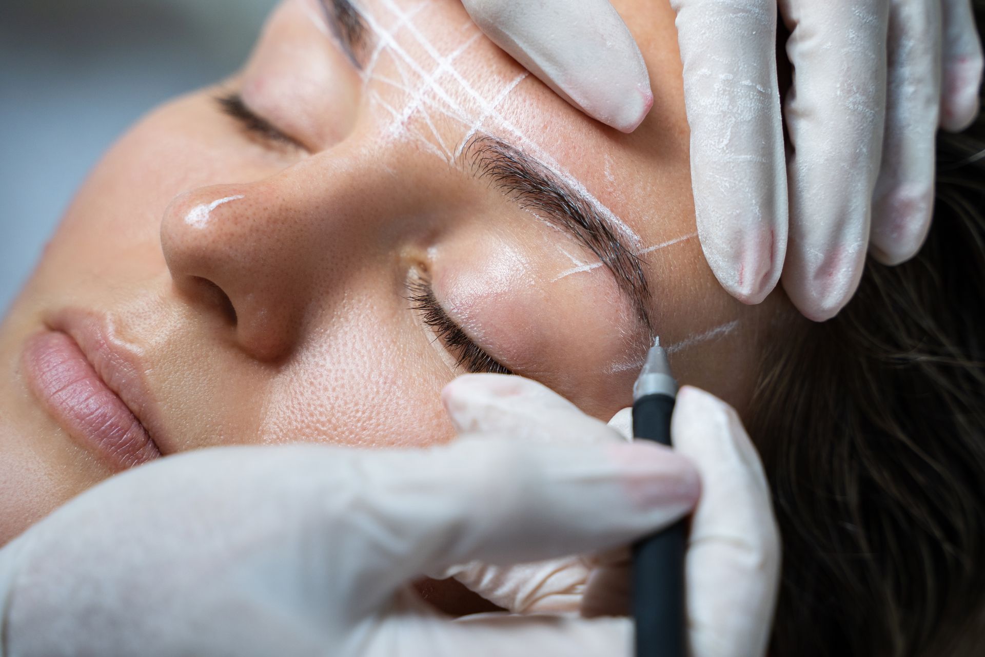 A woman is getting permanent makeup on her eyebrows.