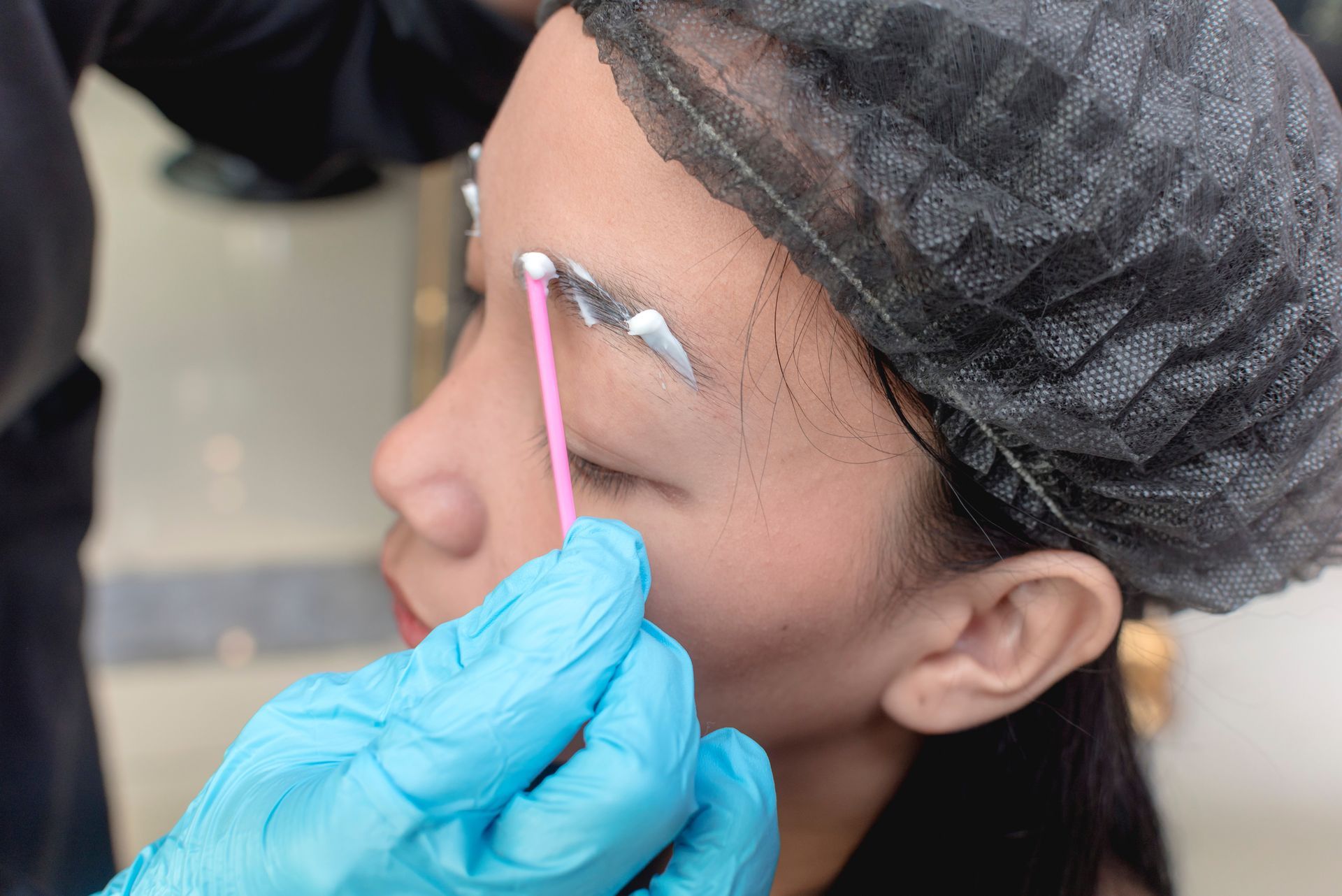 Microblading Artist Applying Numbing Cream to Eyebrows Before Microblading Procedure