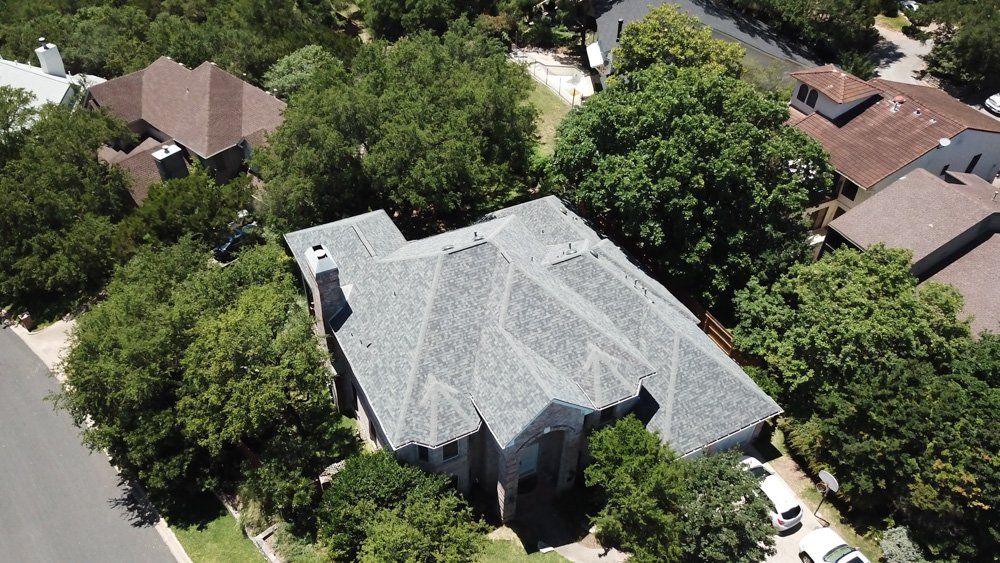 an aerial view of a house in a residential area surrounded by trees .