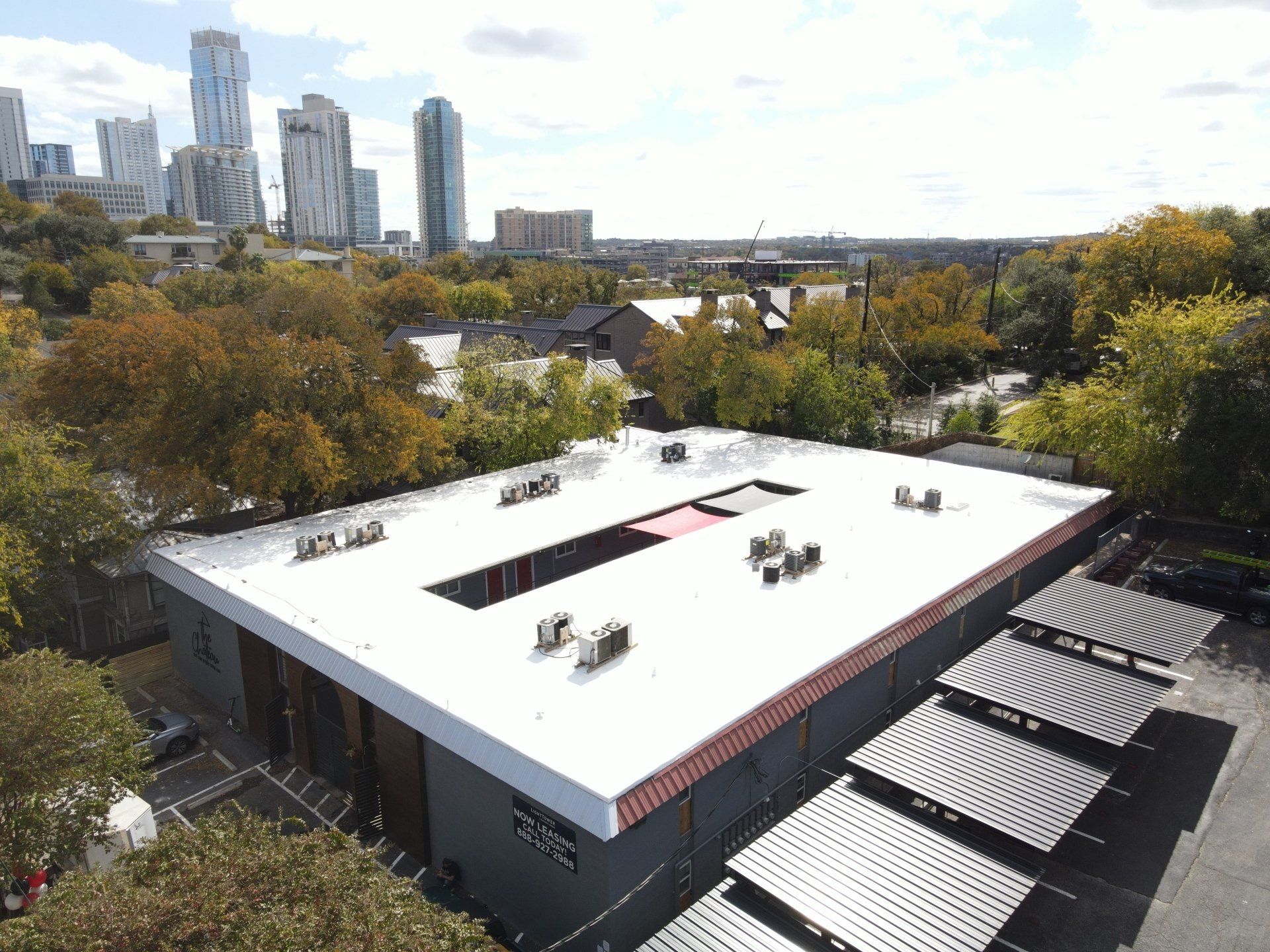 Building with a white roof, solar panels, and cityscape in the background.