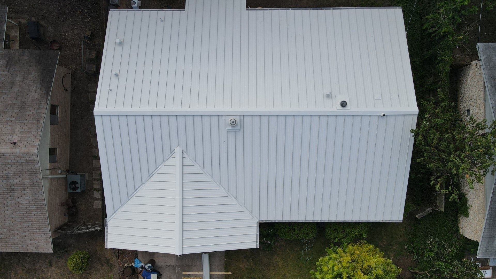 An aerial view of a white house with a metal roof.