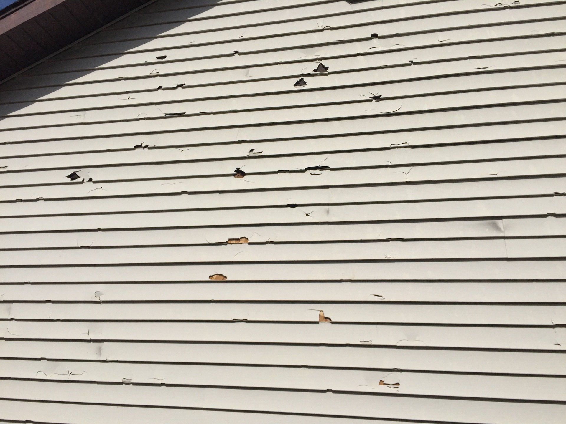 Extreme damage to siding of house after hailstorm
