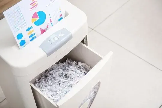 On site Shredding Services in Utah A paper shredder with a piece of paper in it and a drawer filled with shredded paper.