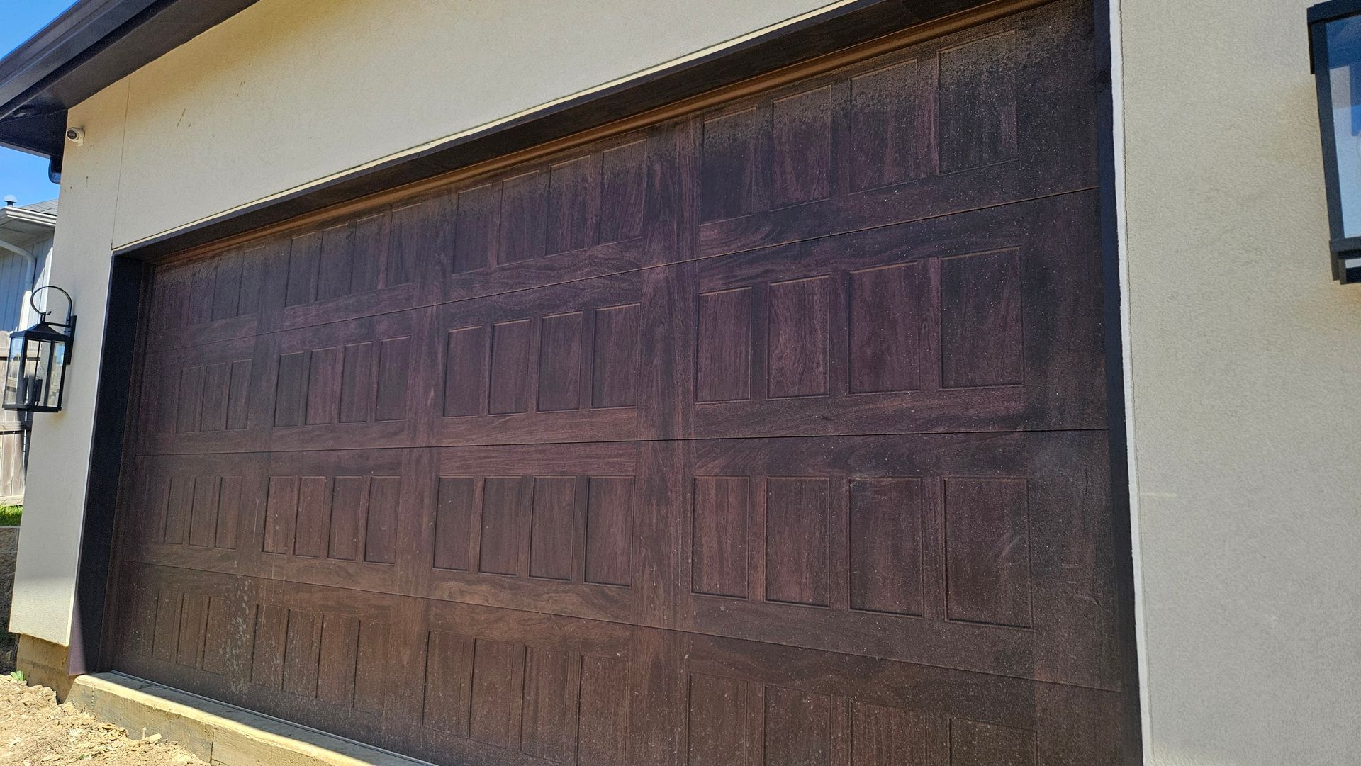 Dark brown garage door with a textured surface, set in a light beige frame.