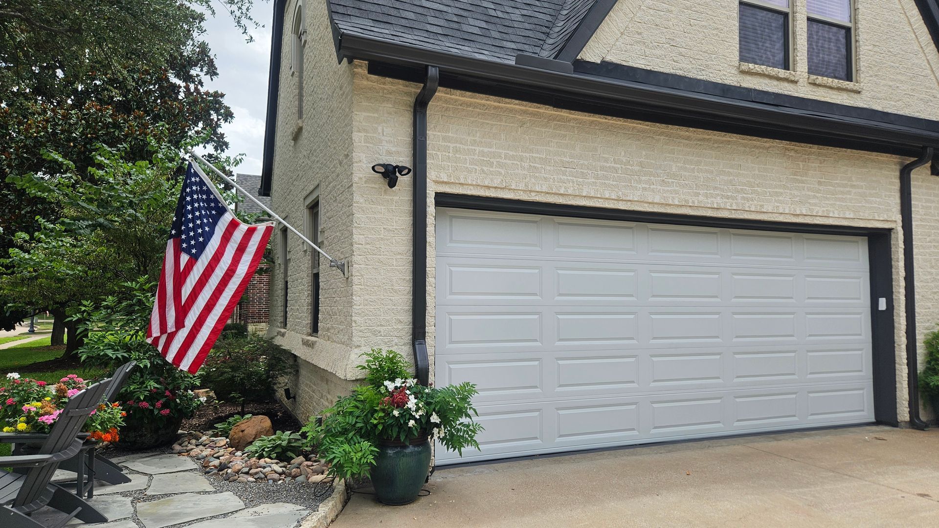 Garage with white door, American flag, and potted plants.