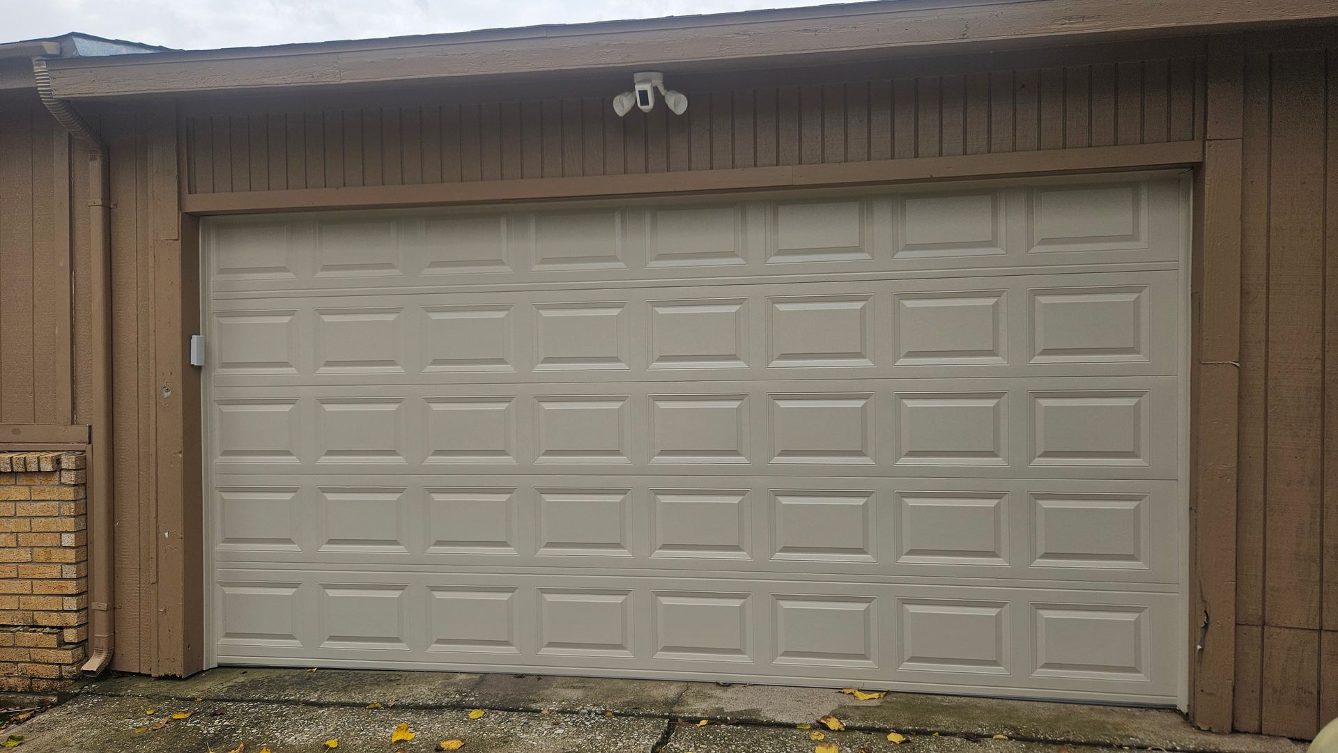 A large brick house with two garage doors and a driveway.