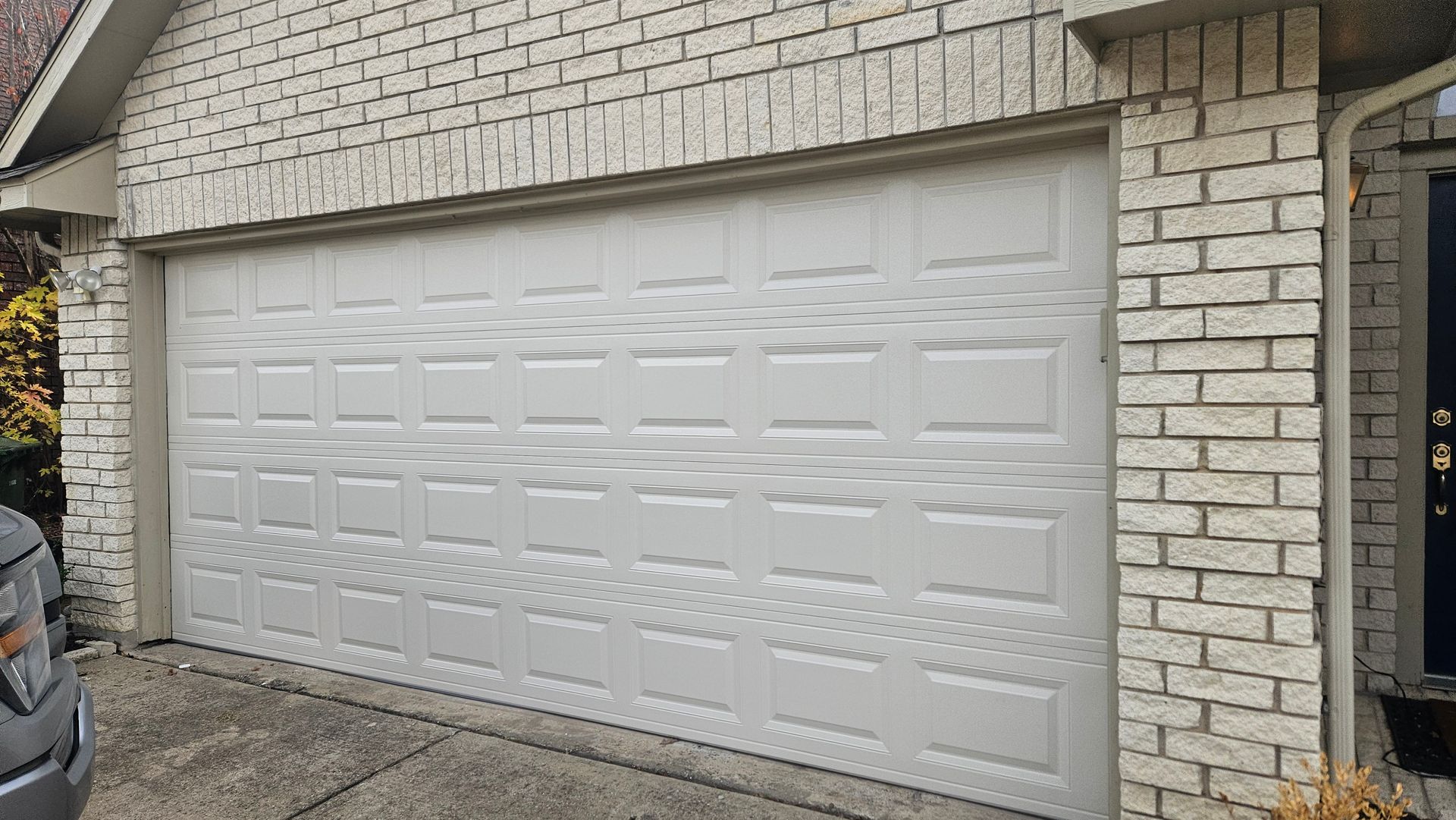 Closed white garage door on a brick house.