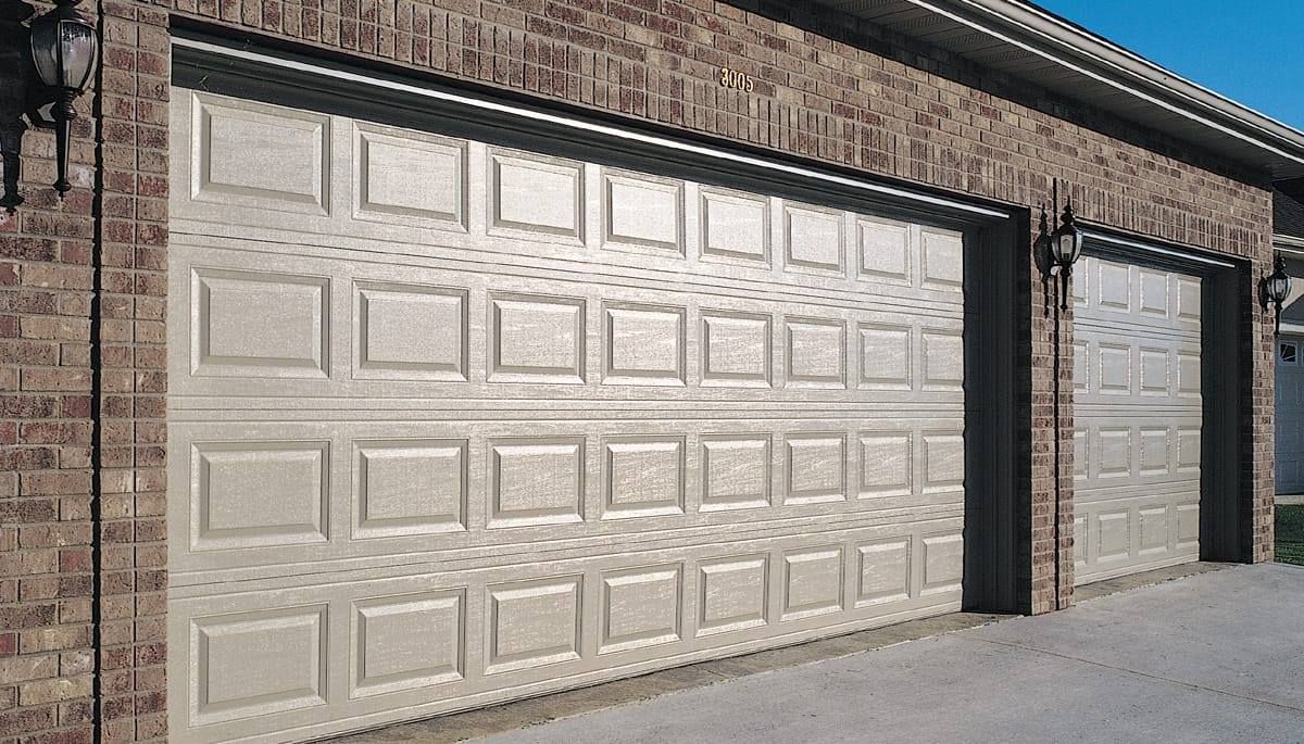 A pair of white garage doors on a brick building.