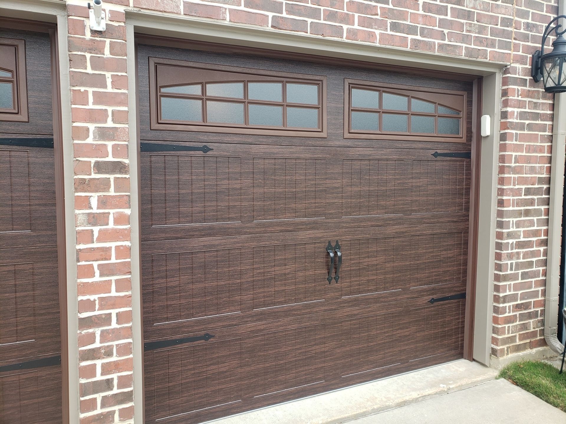 A brown garage door is on a brick building.