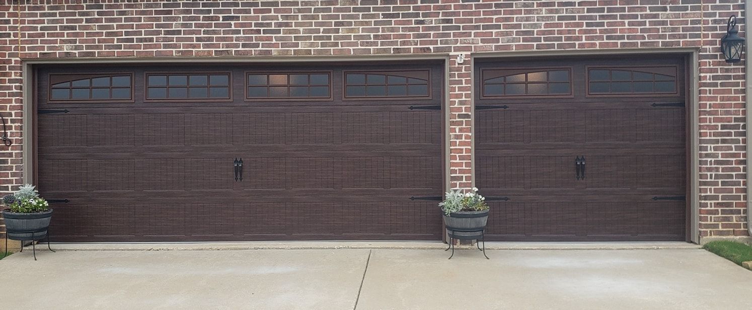 Two brown garage doors are sitting next to each other on a brick building.