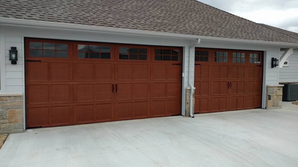 There are three garage doors on the side of a house.