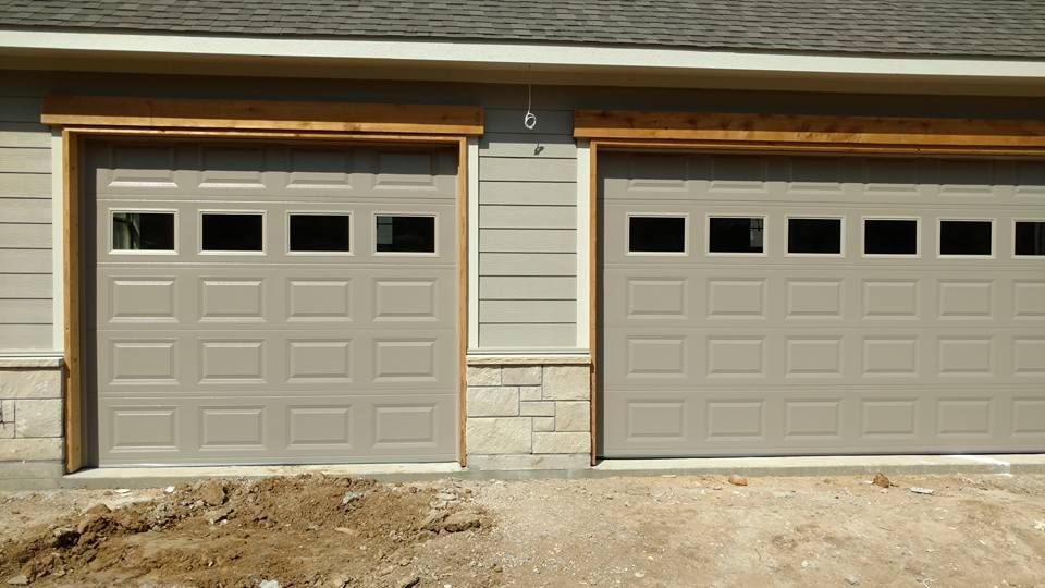 There are two garage doors on the side of a house.