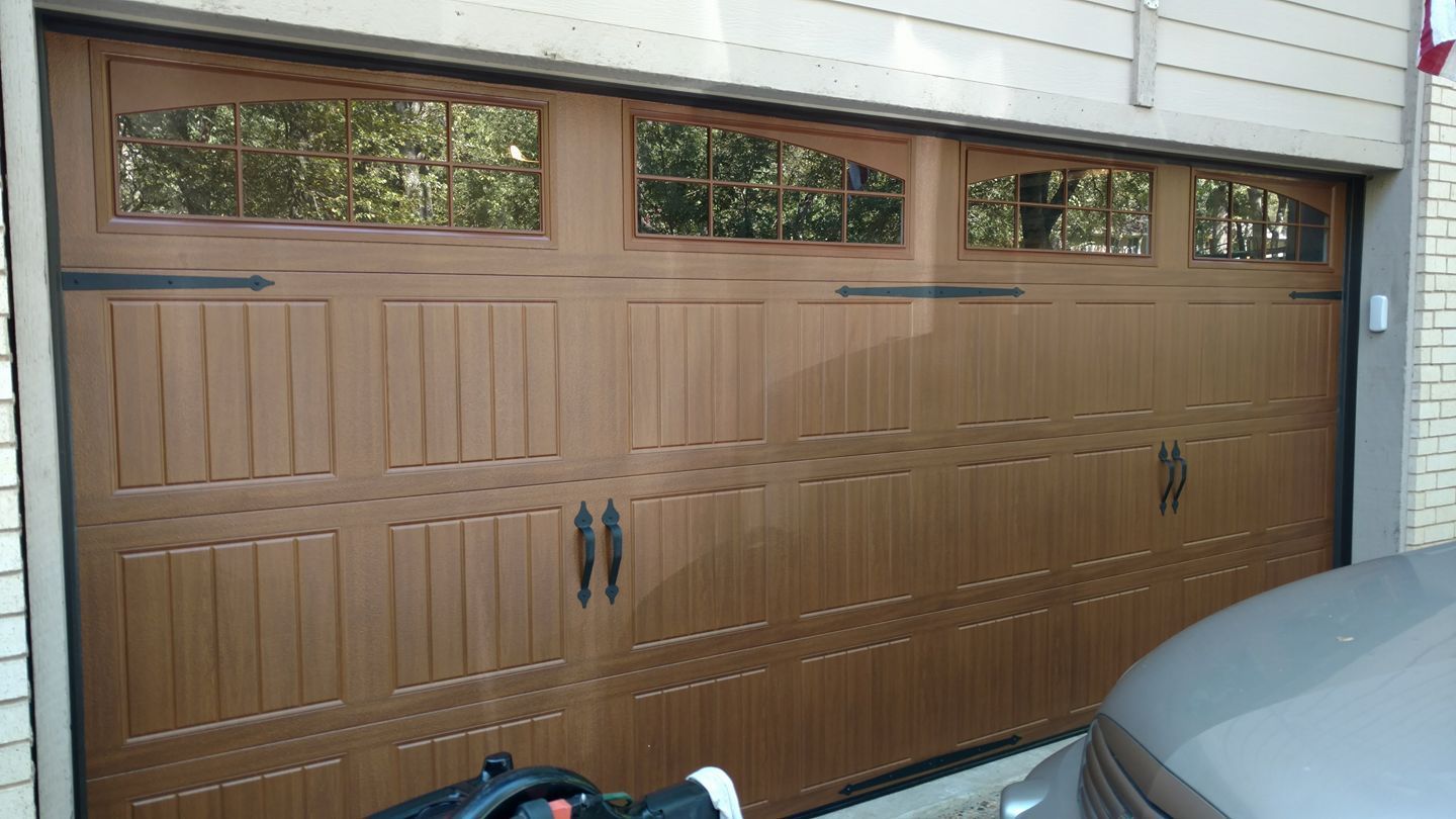 A car is parked in front of a brown garage door.