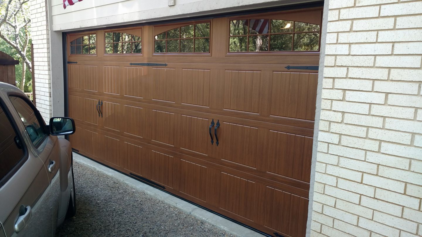 A car is parked in front of a wooden garage door.