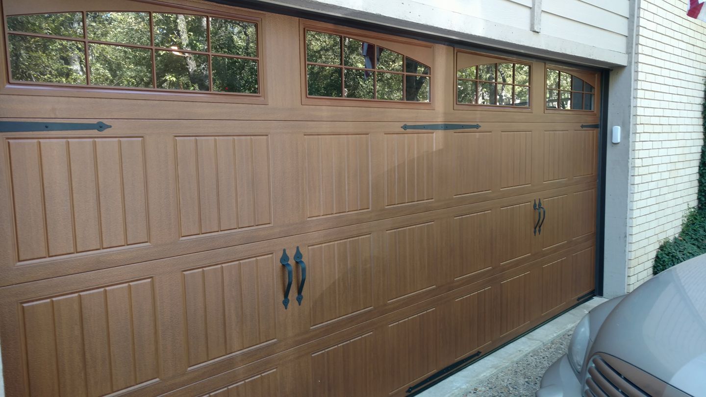A car is parked in front of a wooden garage door.