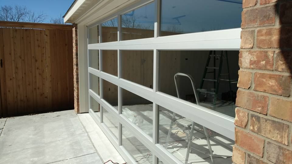 A white garage door is being installed on a brick building.