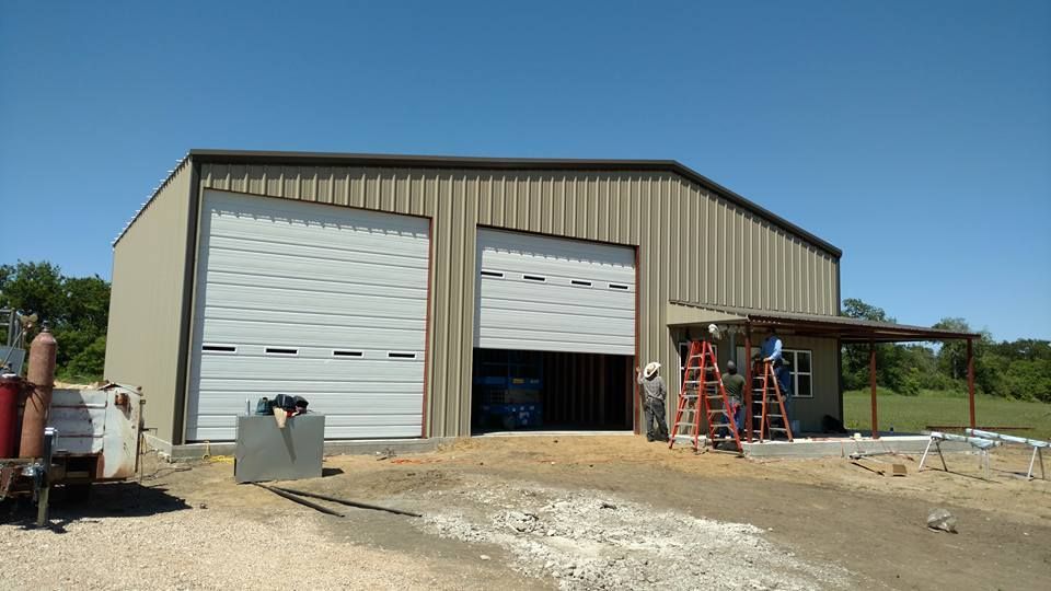 A large metal building with two garage doors and a porch