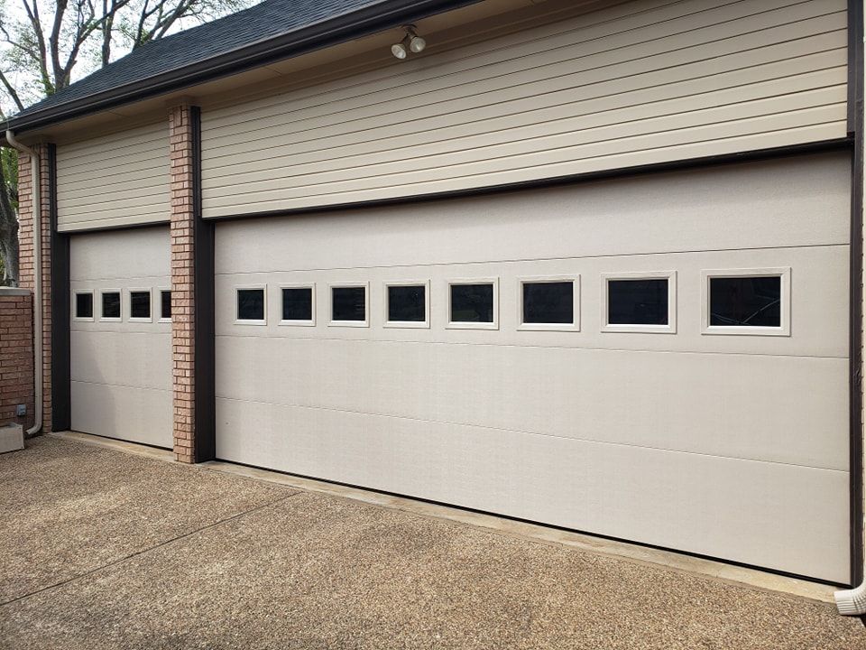 A white garage door with square windows on the side of a house.