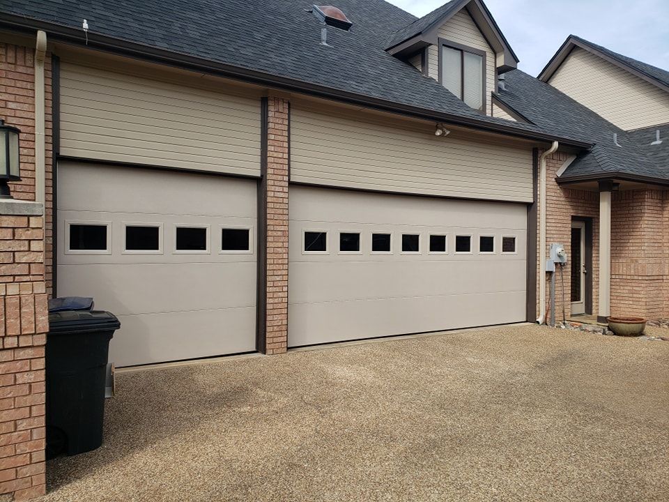 A large garage door is on the side of a brick house.