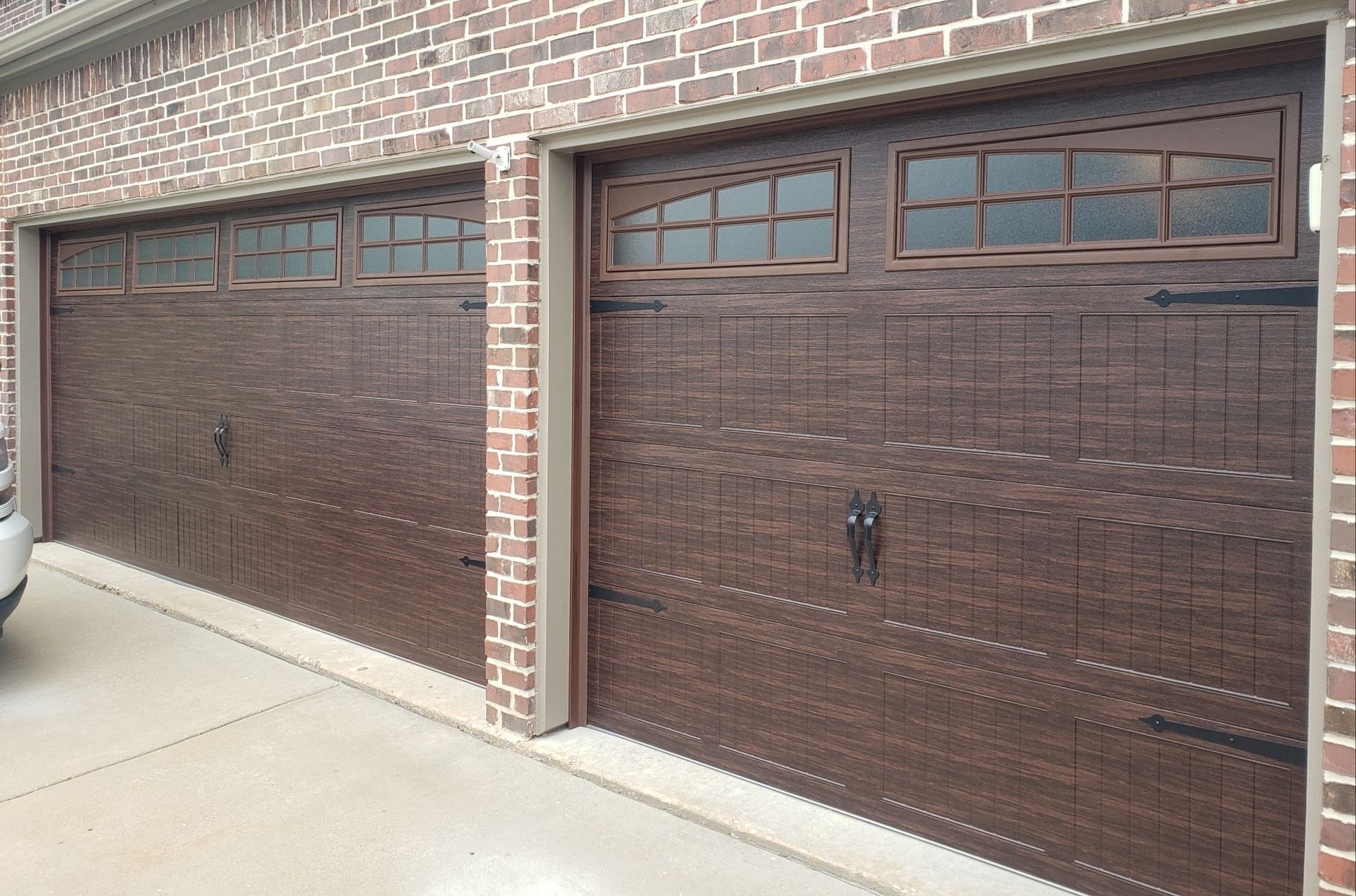 A car is parked in front of a brick garage door.