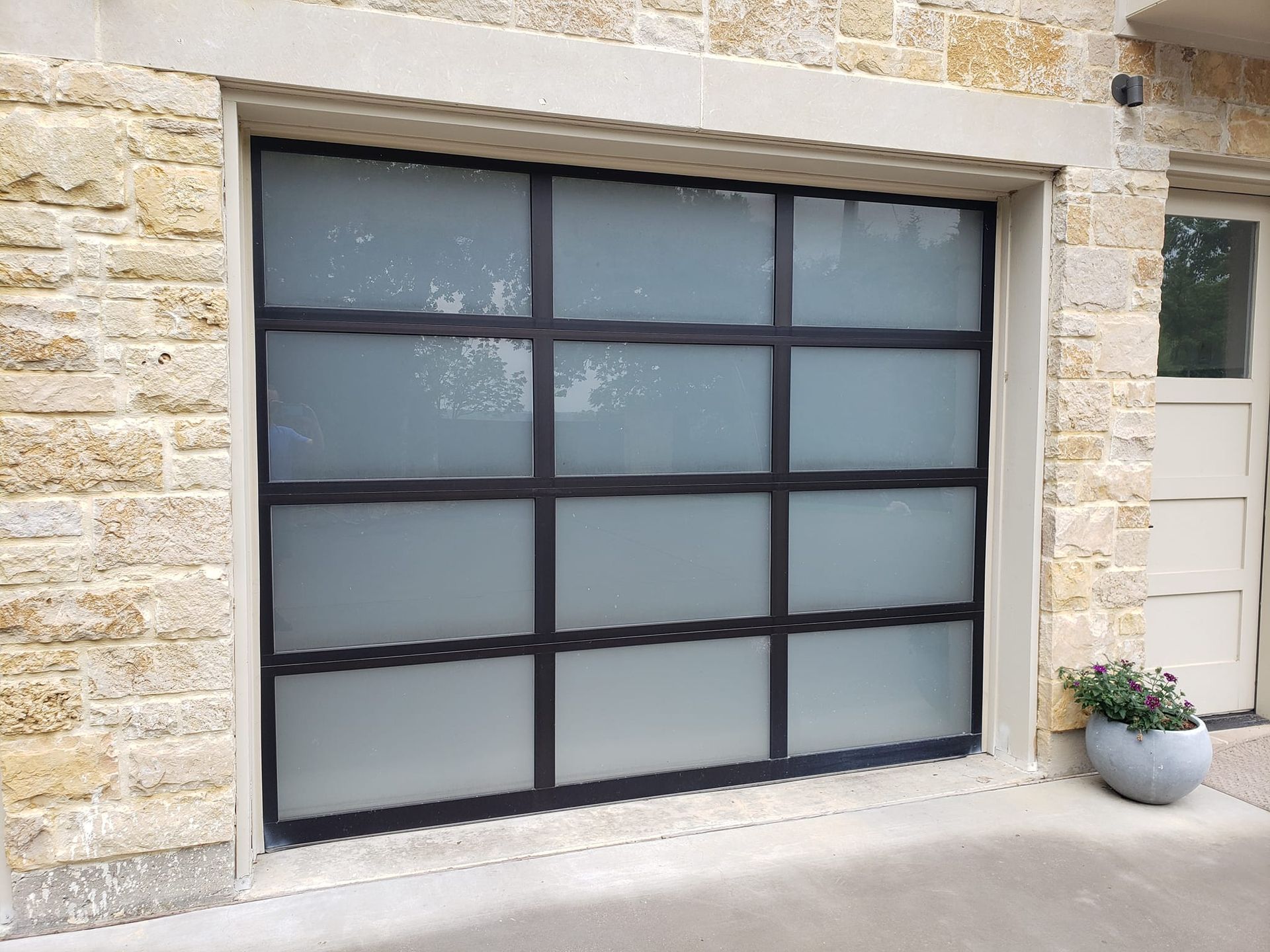 A garage door with a brick wall and a potted plant in front of it.