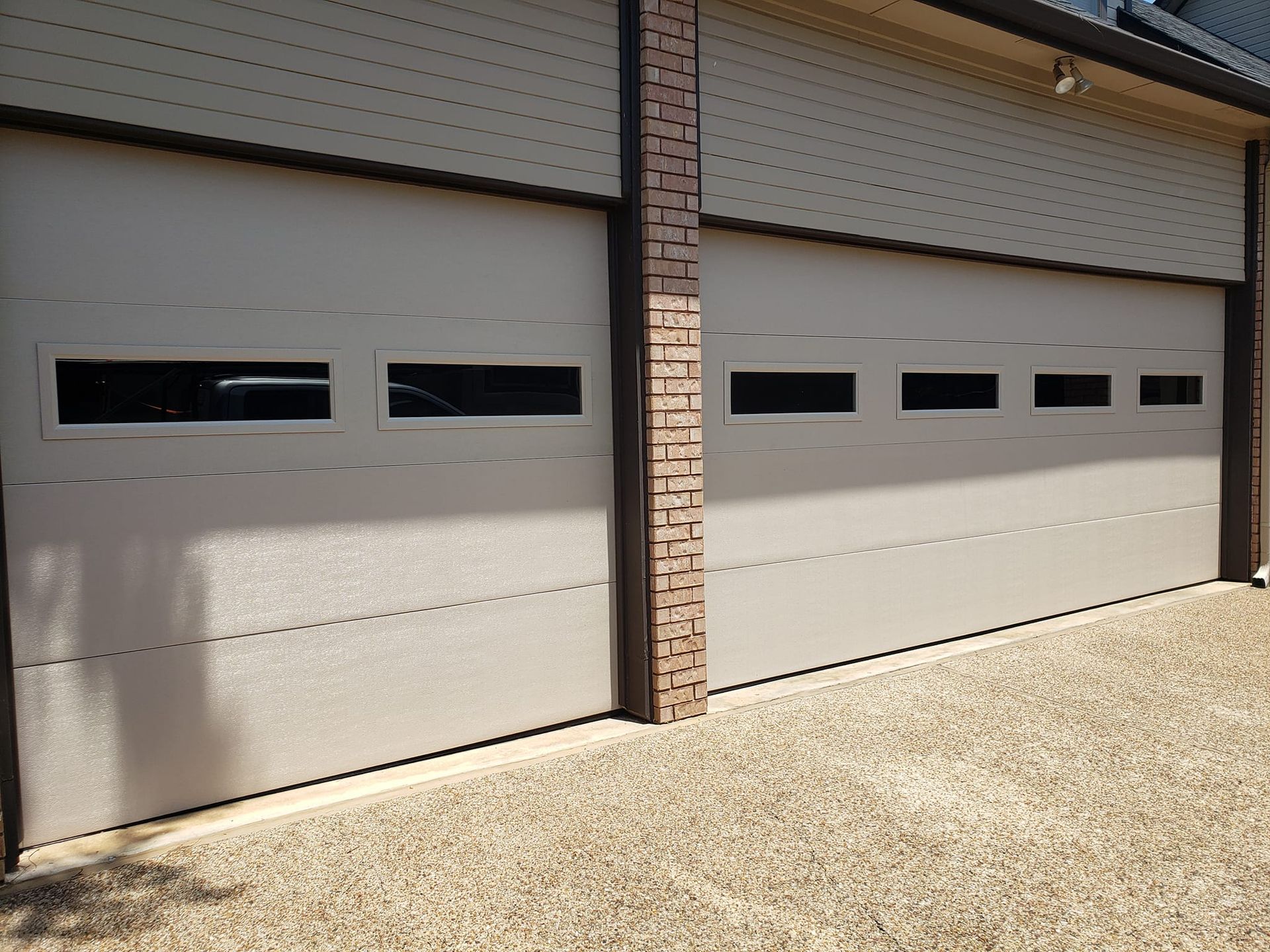 A white garage door with a brick wall behind it