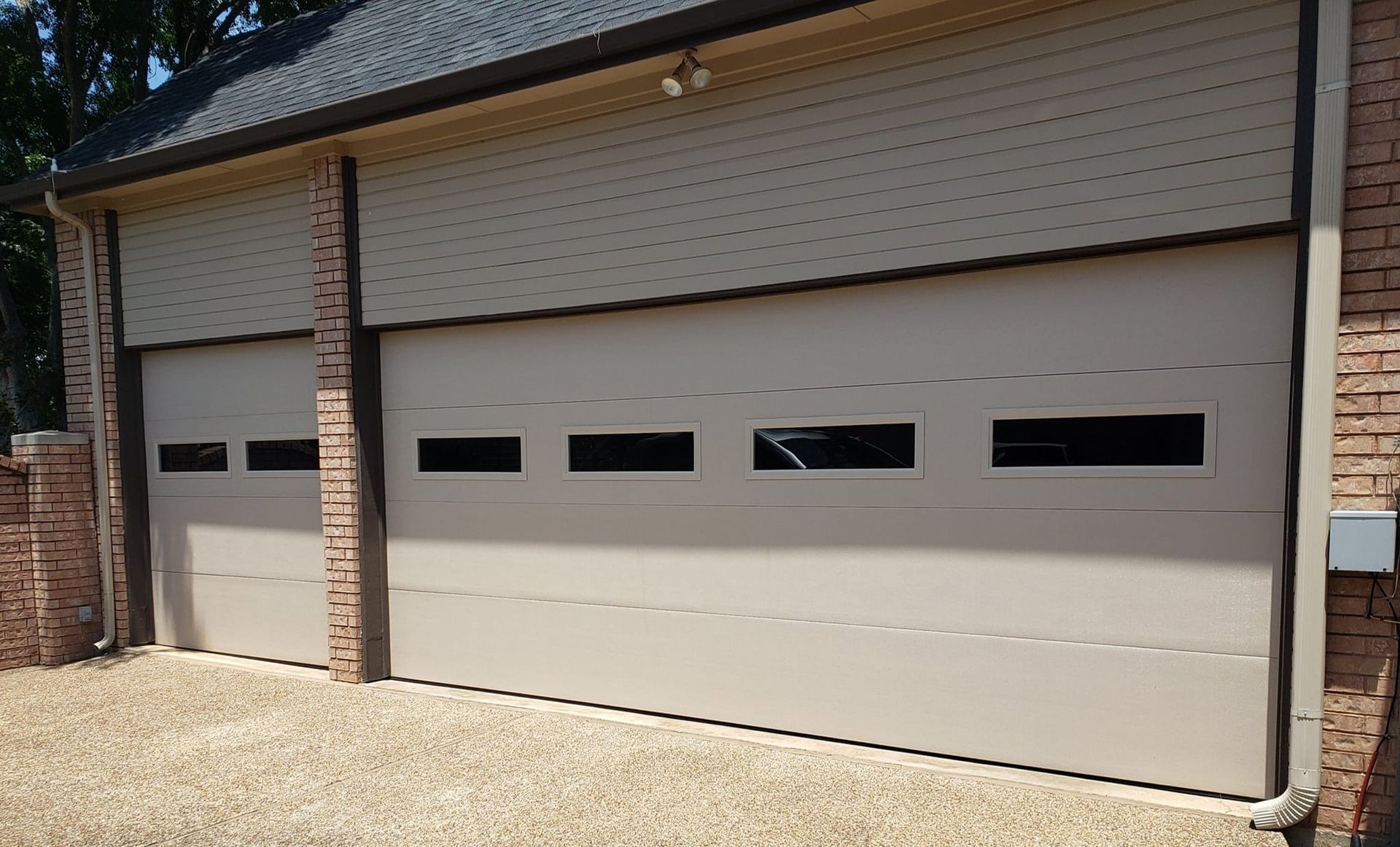 A garage with three garage doors and a brick wall.
