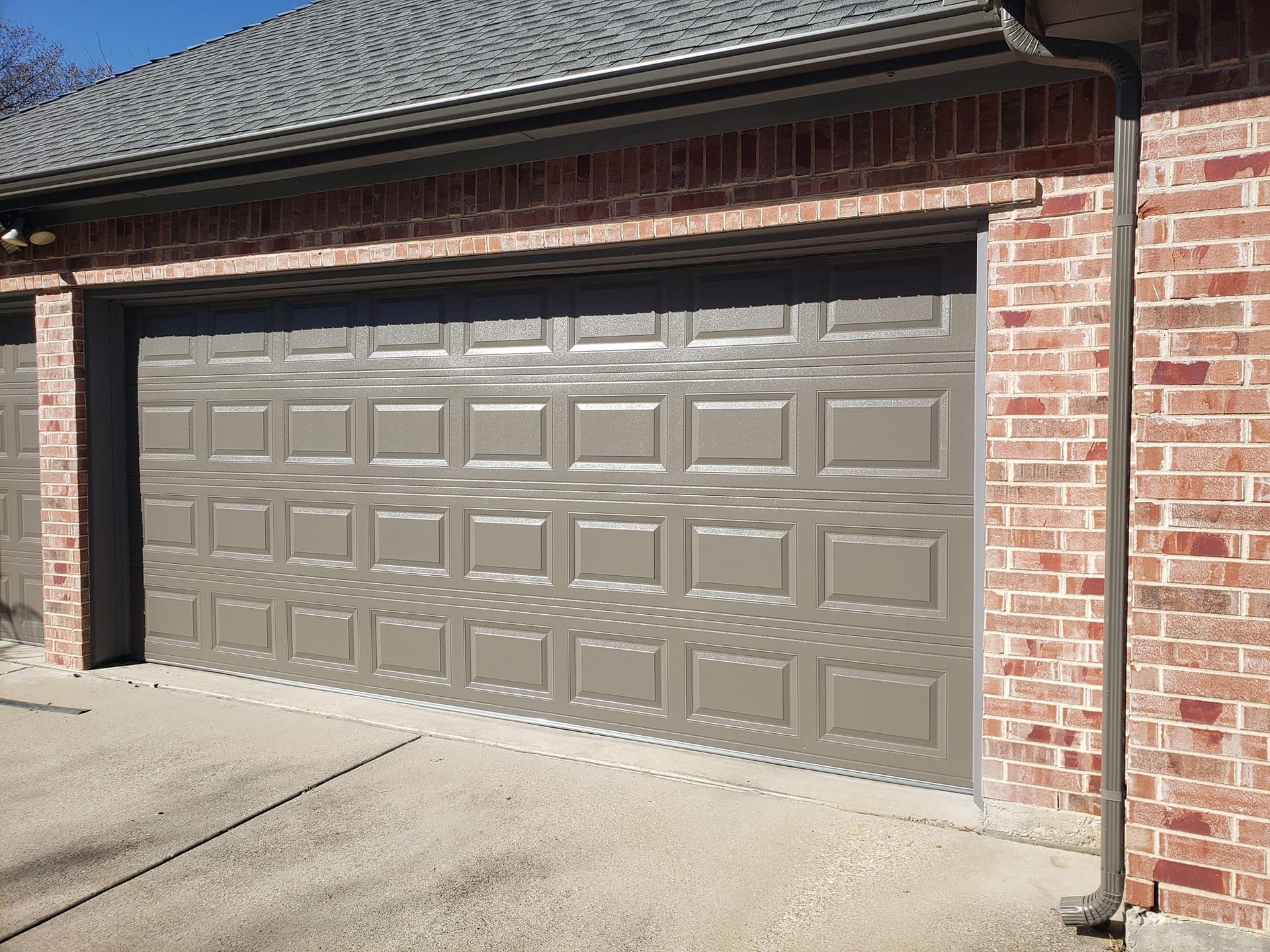 A garage door is sitting on the side of a brick building.