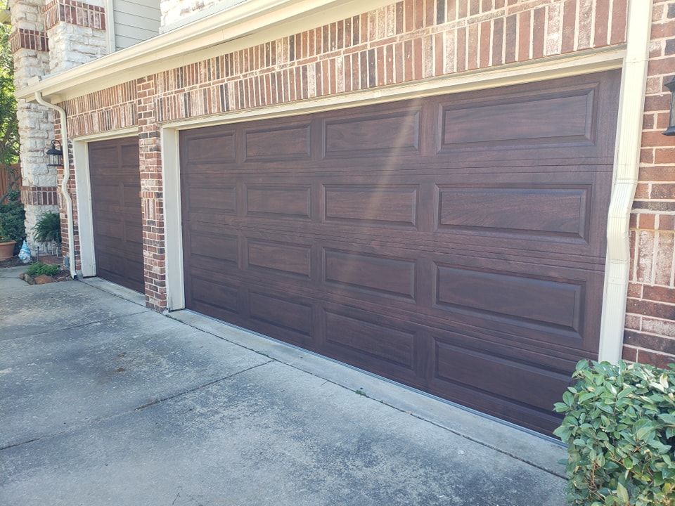 A couple of brown garage doors on a brick building.
