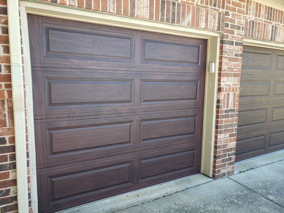 A pair of brown garage doors on a brick building.