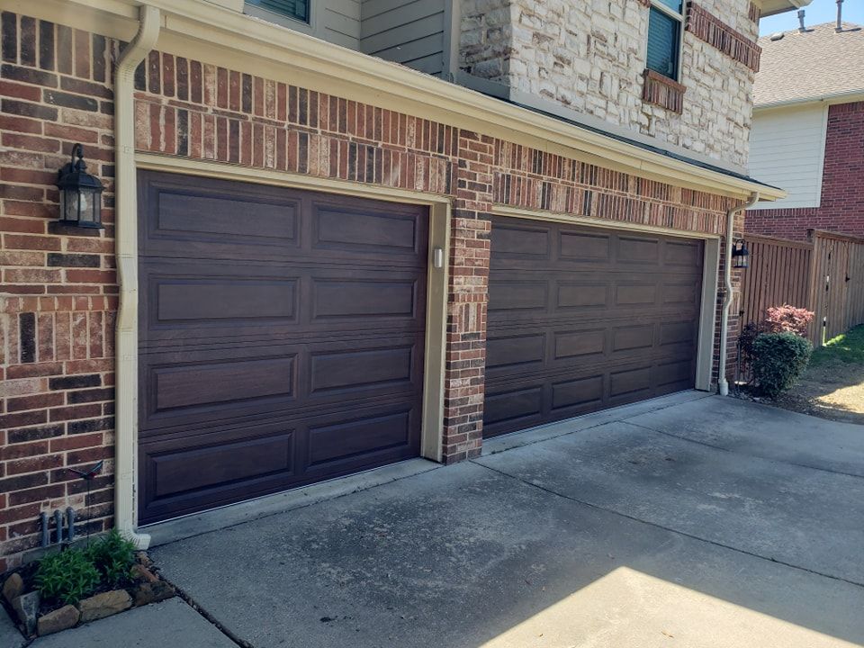 There are three garage doors on the side of a brick building.