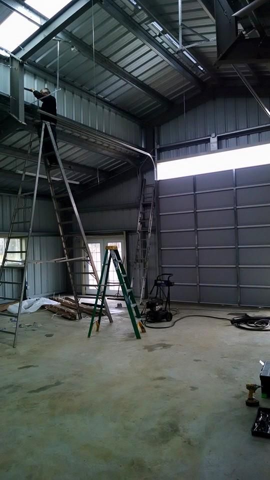 A man is standing on a ladder in a garage.