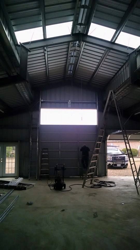 The inside of a garage with a large window and a ladder.