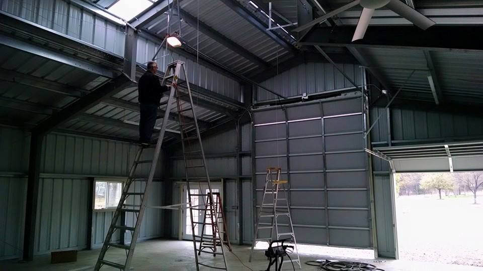 A man is standing on a ladder in a garage.