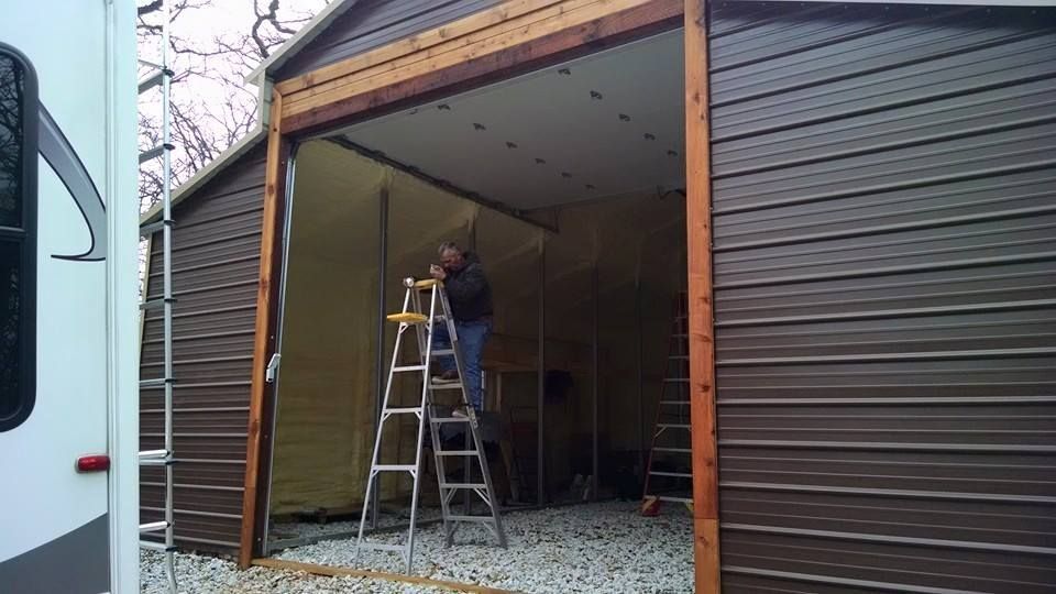 A man is standing on a ladder in front of a garage door.