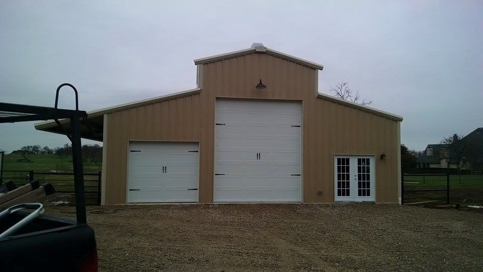 A truck is parked in front of a building with two garage doors