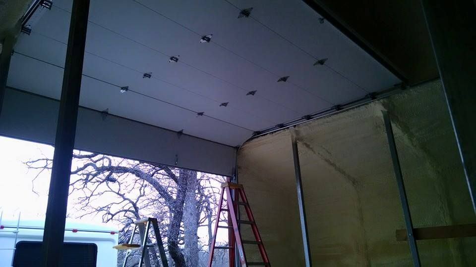 A garage door is being repaired with a ladder in the background