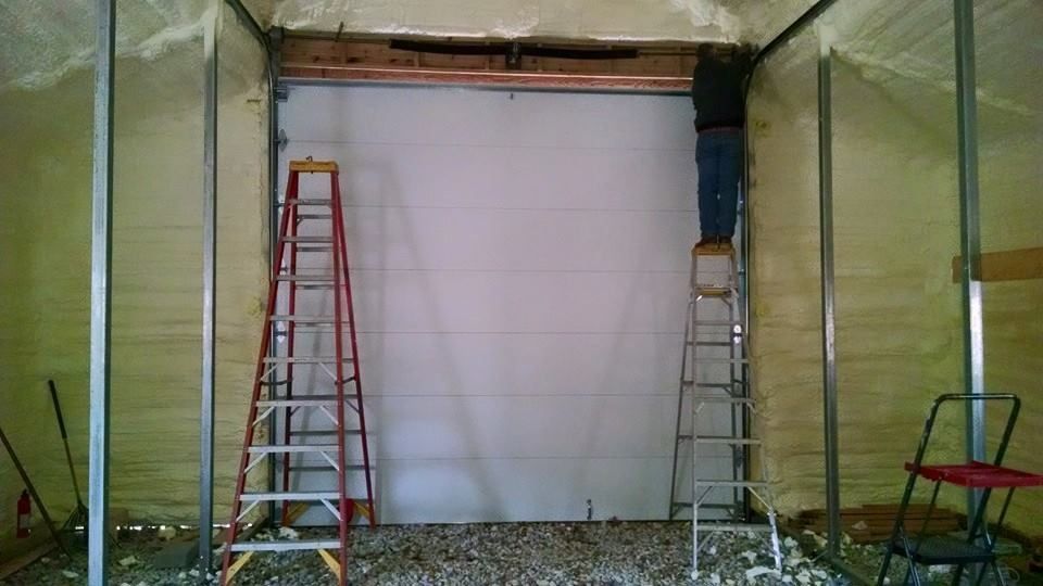A man is standing on a ladder in front of a garage door