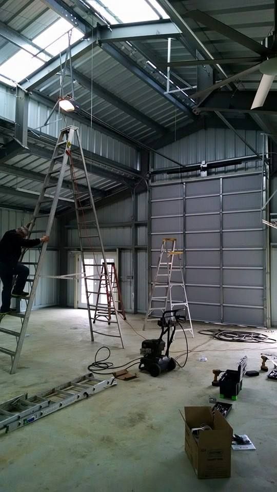 A man is standing on a ladder in a garage.