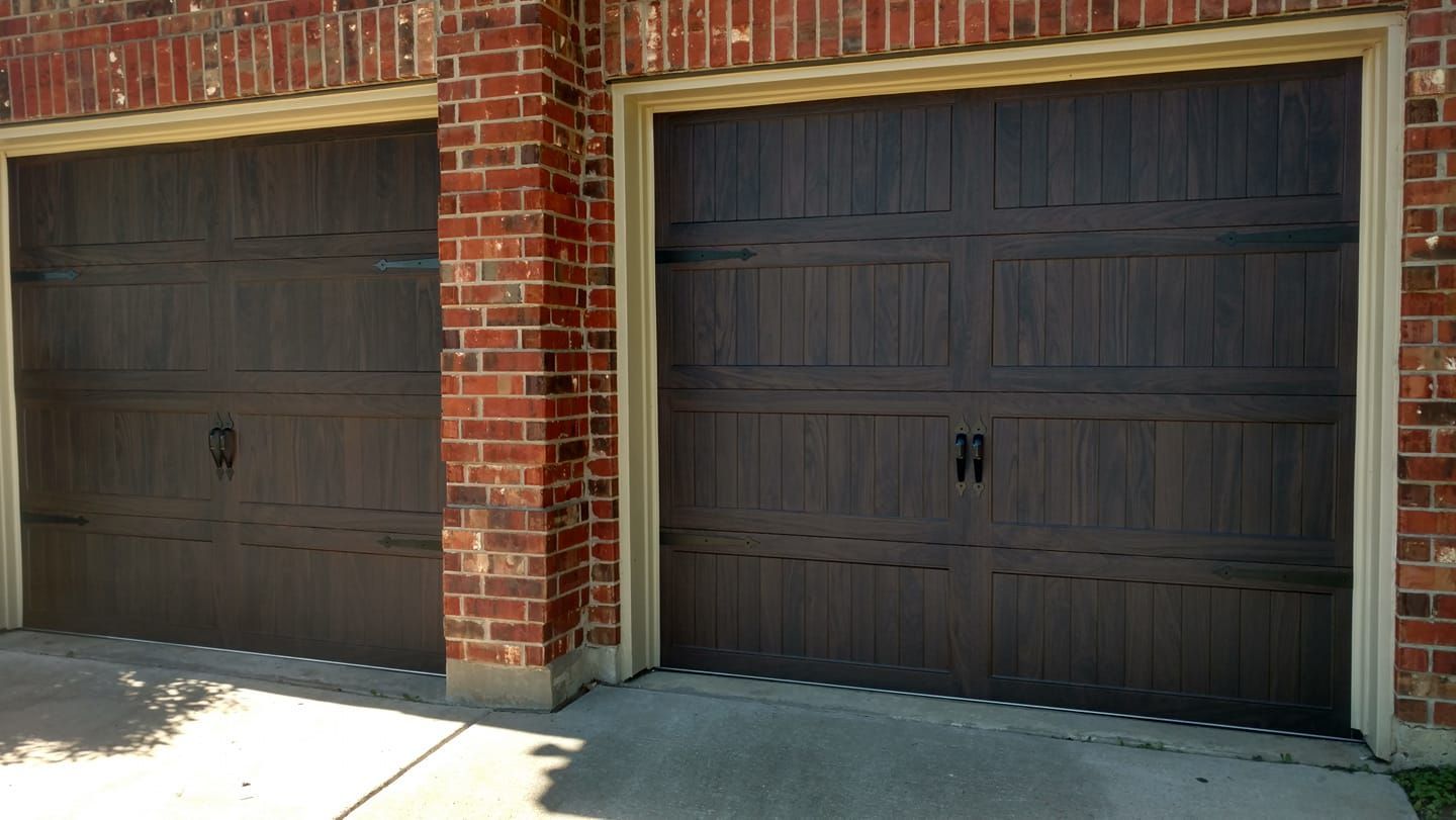 Two brown garage doors are sitting next to each other in front of a brick building.