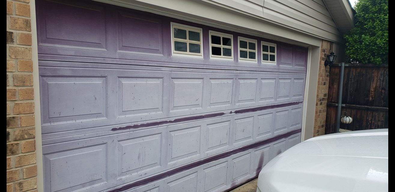 A purple garage door with a white truck parked in front of it.